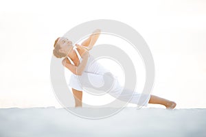 Caucasian woman practicing yoga at seashore