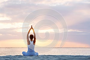 Caucasian woman practicing yoga at seashore