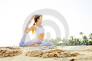 Caucasian woman practicing yoga at seashore of tropic ocean