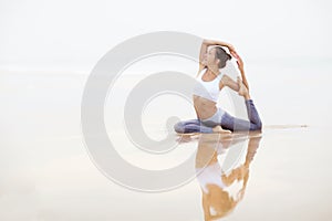 Caucasian woman practicing yoga at seashore of tropic ocean