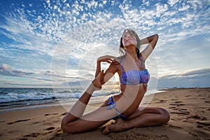 Caucasian woman practicing yoga at seashore of tropic ocean