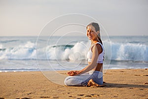 Caucasian woman practicing yoga at seashore of tropic ocean