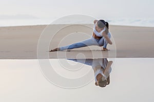 Caucasian woman practicing yoga at seashore of tropic ocean