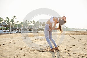 Caucasian woman practicing yoga at seashore of tropic ocean