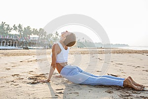 Caucasian woman practicing yoga at seashore of tropic ocean