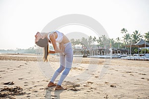 Caucasian woman practicing yoga at seashore of tropic ocean