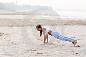 Caucasian woman practicing yoga at seashore of tropic ocean