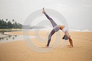 Caucasian woman practicing yoga at seashore of tropic ocean