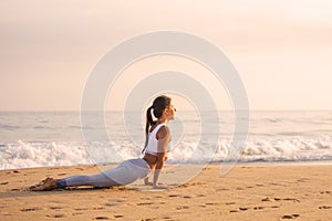 Caucasian woman practicing yoga at seashore of tropic ocean