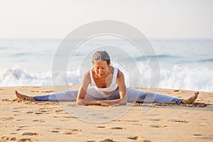 Caucasian woman practicing yoga at seashore of tropic ocean