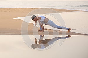 Caucasian woman practicing yoga at seashore of tropic ocean