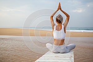 Caucasian woman practicing yoga at seashore of tropic ocean