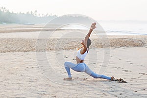 Caucasian woman practicing yoga at seashore of tropic ocean