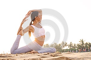 Caucasian woman practicing yoga at seashore of tropic ocean