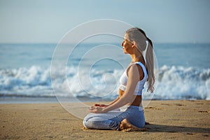 Caucasian woman practicing yoga at seashore of tropic ocean