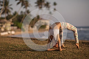 Caucasian woman practicing yoga at seashore of tropic ocean