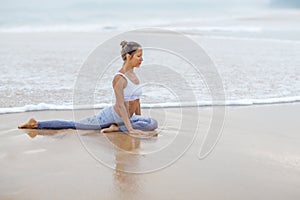 Caucasian woman practicing yoga at seashore of tropic ocean