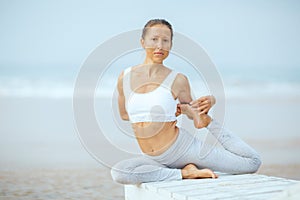 Caucasian woman practicing yoga at seashore of tropic ocean