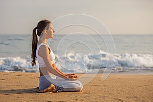 Caucasian woman practicing yoga at seashore of tropic ocean