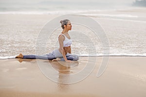 Caucasian woman practicing yoga at seashore of tropic ocean