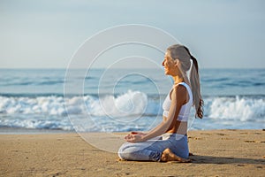 Caucasian woman practicing yoga at seashore of tropic ocean