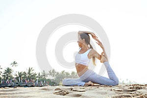 Caucasian woman practicing yoga at seashore of tropic ocean