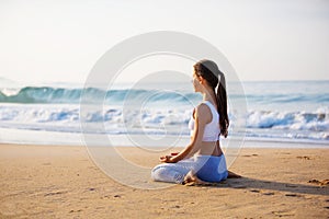 Caucasian woman practicing yoga at seashore of tropic ocean