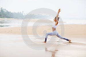 Caucasian woman practicing yoga at seashore of tropic ocean