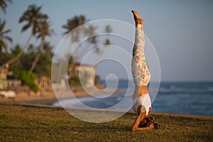 Caucasian woman practicing yoga at seashore of tropic ocean