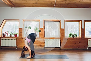 Caucasian woman is practicing yoga at studio padahastasana .