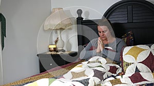 A Caucasian woman praying in her bed - Christianity concept