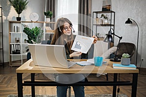 Caucasian woman presenting financial report to colleagues through video call on laptop.