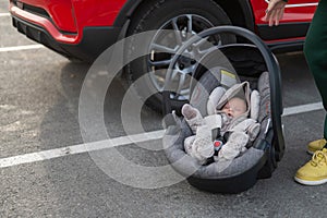 A Caucasian woman puts a child seat with a newborn baby in the car. Quick fastener.