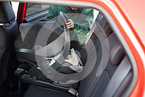 A Caucasian woman puts a child seat with a newborn baby in the car. Quick fastener.