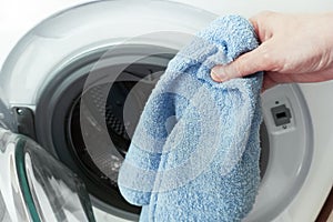 Caucasian woman puts clothes in  washing machine close-up