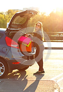 Caucasian woman putting her shopping bags into the car trunk