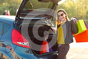 Caucasian woman putting her shopping bags into the car trunk