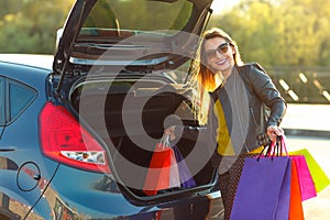 Caucasian woman putting her shopping bags into the car trunk