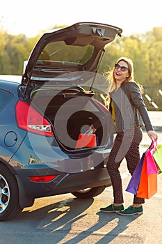 Caucasian woman putting her shopping bags into the car trunk