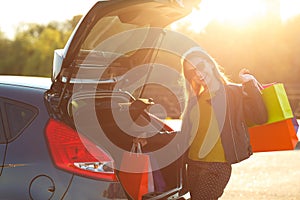 Caucasian woman putting her shopping bags into the car trunk