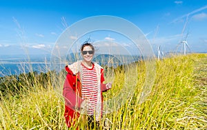 Caucasian woman with red coat and sunglasses stand in the meadow with happiness and smiling