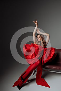 Caucasian woman in red, seated, modern chair, copy space.