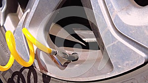 A caucasian woman is removing the stem valve cap and attaching the yellow spiral tubing of a 12v car air compressor