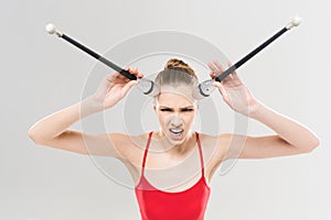 Caucasian woman rhythmic gymnast holding clubs with facial expression