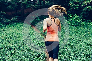 Caucasian woman running on forest trail wearing sport clothes