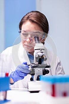 Caucasian woman scientist in white coat looking in high end microscope