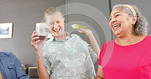 Caucasian woman and senior biracial woman share a joyful moment with drinks and snacks