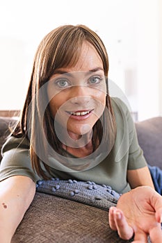 Caucasian woman with shoulder-length brown hair is smiling at the camera on a video call