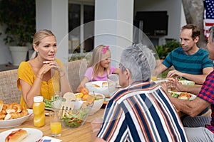 Caucasian woman sitting at table talking with family having meal in garden