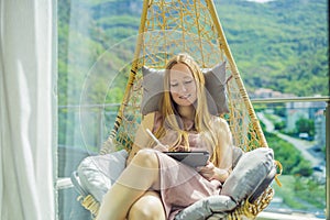 Caucasian woman sitting on the terrace working from home using computer laptop. Young woman teaches a foreign language